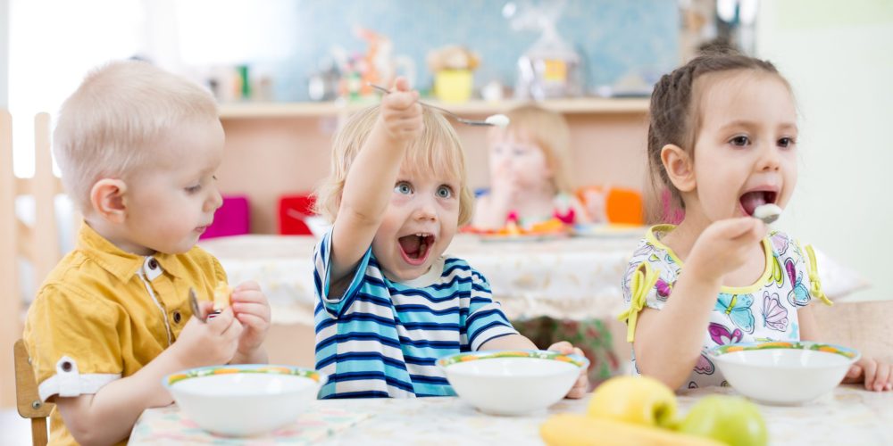 funny kids group eating in kindergarten